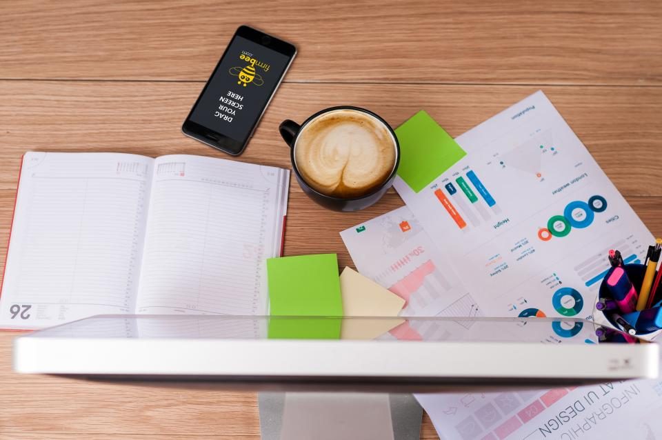 Printed charts and reports on a desk with a coffee and a notebook